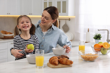 Sticker - Mother and her cute little daughter having breakfast at table in kitchen