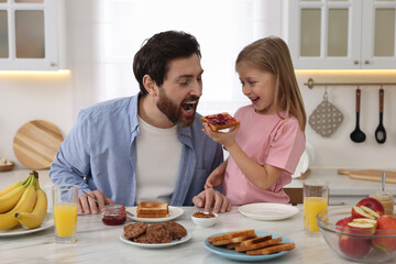 Sticker - Father and his cute little daughter having fun during breakfast at table in kitchen