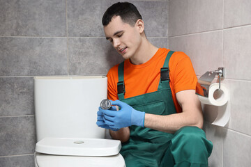 Sticker - Young plumber repairing toilet bowl in water closet