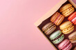 © Di Studio - colorful macarons in the cardboard box on the pink background with copy space