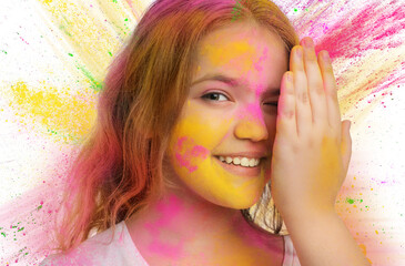 Wall Mural - Holi festival celebration. Happy teen girl covered with colorful powder dyes on white background