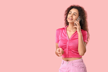 Poster - Young African-American woman talking by phone on pink background