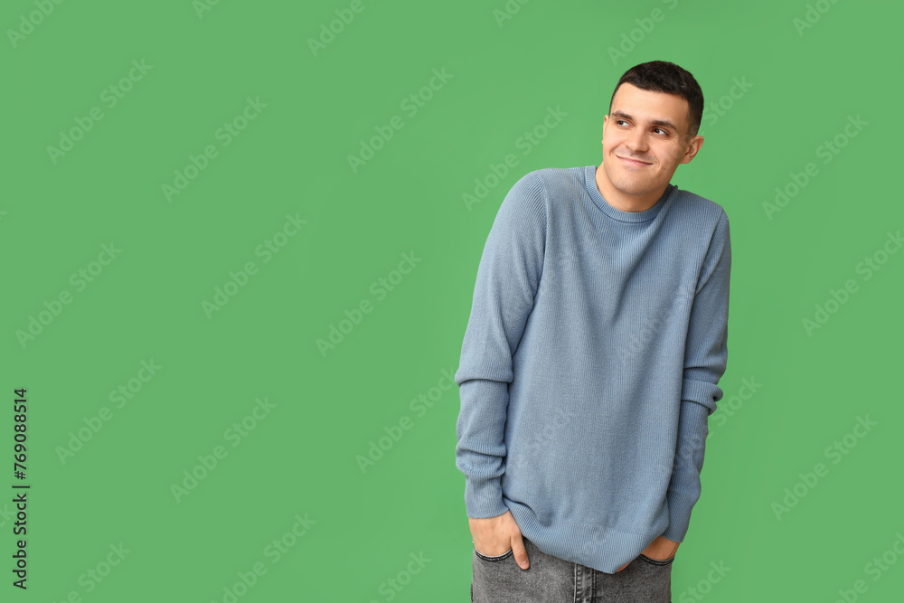 Handsome ashamed young man on green background