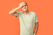 © Pixel-Shot - Handsome ashamed young man covering face with hand on orange background