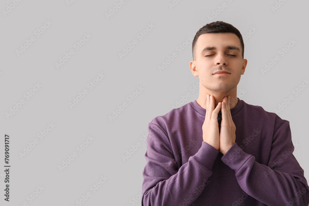 Young man with thyroid gland problem on light background