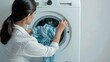 Person loading a washing machine with laundry.