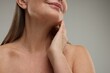 © New Africa - Mature woman touching her neck on grey background, closeup
