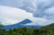 Panorama of Mount Agung and rice fields on the island of Bali. View of the mountain against a background of palm trees and a cornfield. Panorama of Agung volcano covered with clouds on a rainy day.