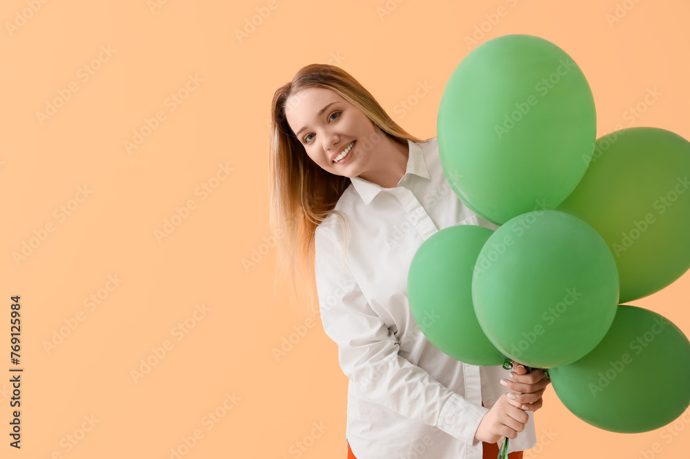 Young woman with balloons on beige background
