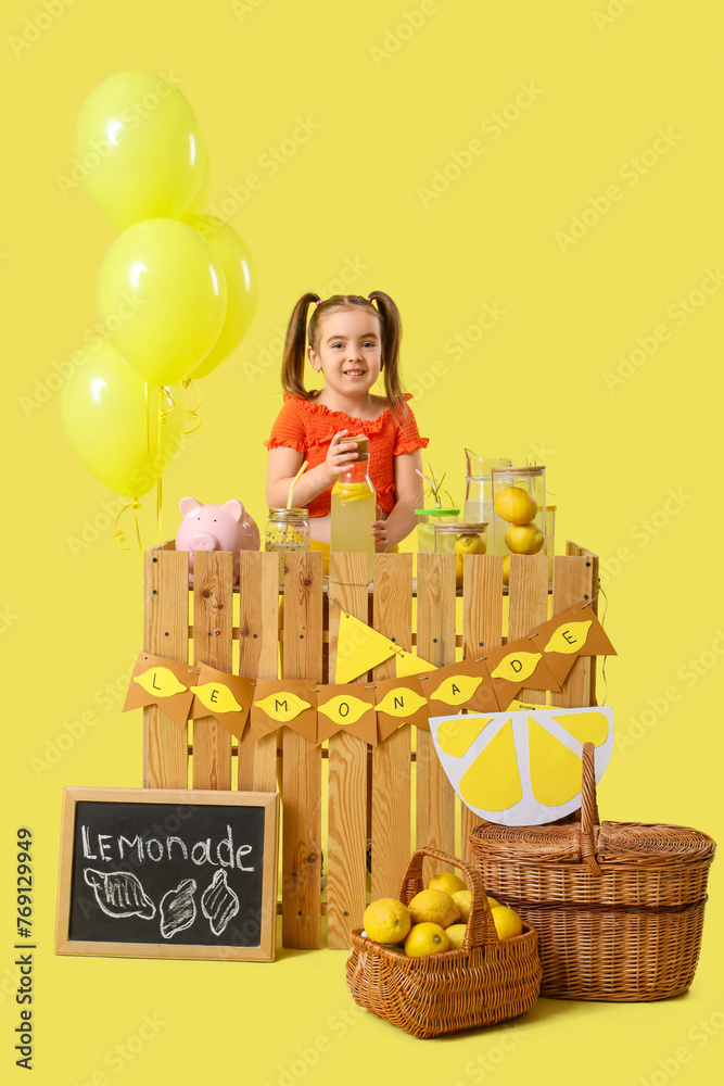 Cute little girl at lemonade stand on yellow background