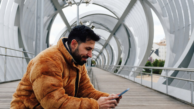 Fashionable Man Holding Phone on Urban Bridge