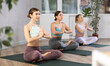 © JackF - Young female yoga instructor showing others lotus pose in wellness center
