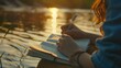 In the tranquil evening by the riverside, a young woman's hand elegantly writes with a pen on her notebook, Ai Generated