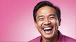 young indonesian middle age man on plain bright pink background laughing hysterically looking at camera background banner template ad marketing concept from Generative AI