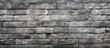 A close up of a rectangular grey brick wall showcasing the intricate brickwork pattern. The monochrome photography highlights the composite material of the stone wall