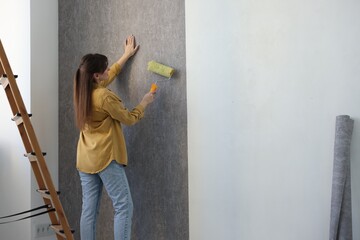 Poster - Woman hanging stylish gray wallpaper in room