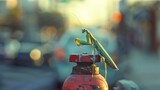 Fototapeta  - Perched atop a fire hydrant a praying mantis patiently waits for its next meal perfectly still and unseen by the hustle and bustle of cars and pedestrians passing by.