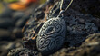 Detailed shot of an ancient-looking tribal pendant with a distinct pattern, resting on dark volcanic rock