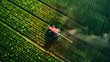 Smart Agriculture: Tractor Spraying Crops with Tech
. An aerial shot of a tractor spraying crops in a field, enhanced by precision agriculture technology and digital monitoring for efficient farming.
