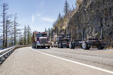 Fototapeta Mapy - Two tree log carrier big rig semi trucks with semi trailers met on a mountain road moving towards each other