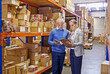 © peopleimages.com - Warehouse, man and woman with tablet, supply chain and inventory with cooperation and industrial. Clipboard, supervisor and management with technology and update schedule with export and cooperation