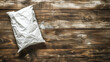 A white bag is sitting on a wooden surface. The bag is torn and crumpled, and it is empty. Concept of abandonment and neglect, as the bag seems to have been discarded or forgotten