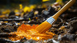 A brush is dipped into a yellow paint and is being used to paint a leaf