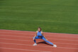 © Yevhen - Female runner stretching before workout. Sports exercises and stretching in the stadium. Physical training girl. Fit girl do outward lunging. Physical training education. Sports lesson