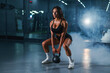 Caucasian woman squats with kettlebell in the gym. 