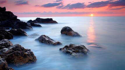 Wall Mural - sunset over the ocean, with rocks and waves gently crashing