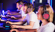 Team of gamers playing video game on PC at computer club, cyber sport tournament. E-sport championship. 5 players in headset communicate with each other over mic. Multiplayer online competition