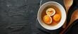 Stewed or hard-boiled eggs with sweet gravy in white bowl with wooden utensils on black background - Thai cuisine setting