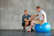 © peopleimages.com - Physical therapy, gym help and exercise ball with a man with a disability and physio consultation for rehabilitation. Physiotherapy and healthcare professional with helping and wellness for mobility