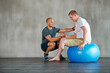 © peopleimages.com - Physical therapy, gym and exercise ball with a man with a disability and physio consultation for rehabilitation. Physiotherapy, help and healthcare professional with helping and wellness for mobility