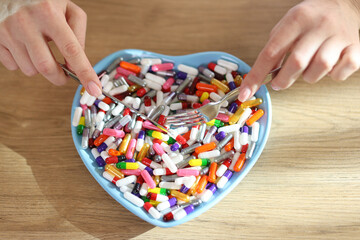 Sticker - Female hands holding table knife and fork above heart shaped bowl with pile of medicine.