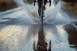 cyclist riding through a puddle, water spraying out