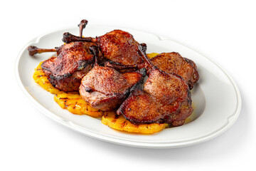 Wall Mural - Grilled duck legs with crispy crust on a bed of grilled pineapples on a white plate. Banquet festive dishes. Gourmet restaurant menu. White background.