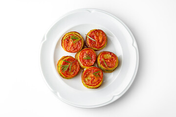 Wall Mural - Ratatouille of zucchini circles, eggplant, tomato on a white plate. Banquet festive dishes. Gourmet restaurant menu. White background.
