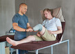 © peopleimages.com - Therapist, man with disability or prosthetic in recovery, wellness or medical fitting in hospital. Bed, people or leg in support, help or healthcare as physio, assessment or orthopedic rehabilitation