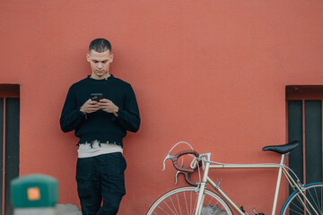 Wall Mural - young man with bicycle on the street with mobile phone