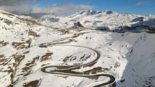 Aerial view of Grossgloknershtrasse in snow. Great high mountain road near Grossglokner mount in Austrian Alps. Blue skies.