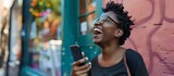 Fototapeta Panele - african american woman using mobile phone on the street smiling happy