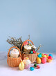 Easter holiday background. wicker basket with Easter cakes, colorful eggs and willow branches on table. Festive composition for Easter.