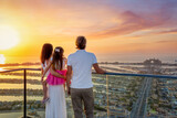 Fototapeta Londyn - A family on holidays enjoys the beautiful view of The Palm island in Dubai, UAE, during a golden sunset