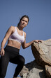 A person in athletic wear is climbing rocks under a clear blue sky, showcasing outdoor physical activity and adventure
