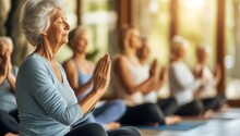 Serene Senior Woman Practicing Yoga With Group In Bright Studio. Concept Of Healthy Active Aging, Mindfulness And Inner Peace.