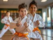 Two young girls in karate uniforms with orange belts performing martial arts forms with focus and enjoyment.