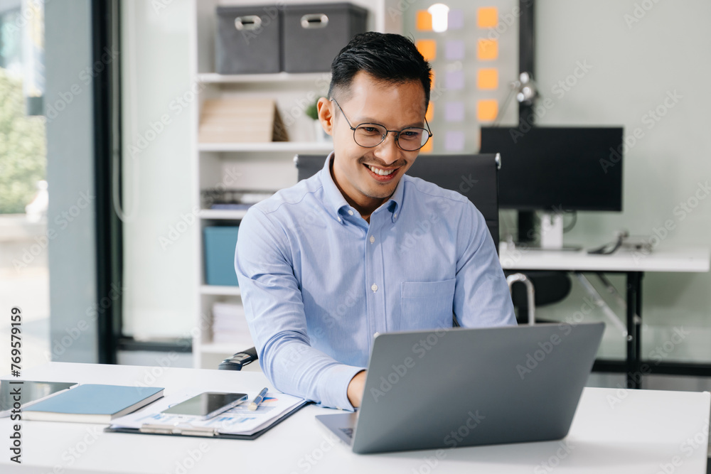Asian man using laptop and tablet while sitting at her working place ...