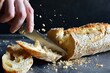 person slicing a crusty baguette, crumbs scattering