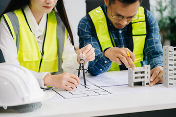 Engineer teams meeting working together wear worker helmets hardhat with on architectural project site and making model house. Asian industry professional team